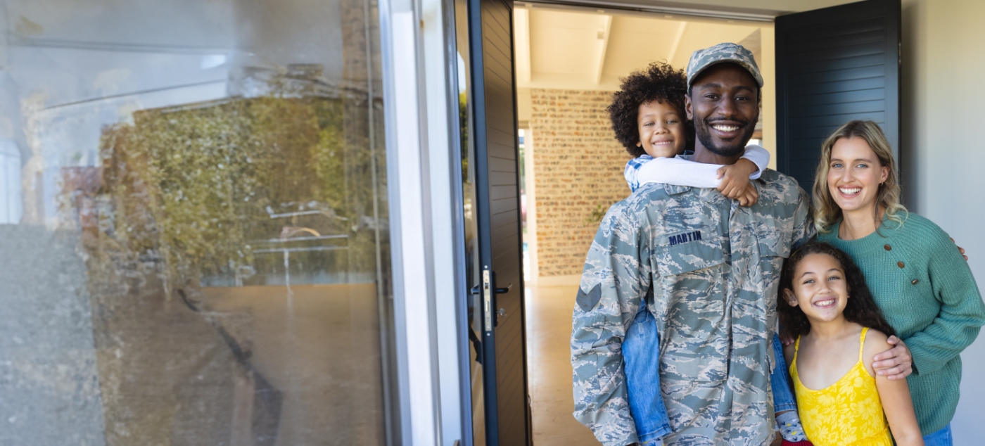 Man in U S army uniform smiling with his wife and two kids