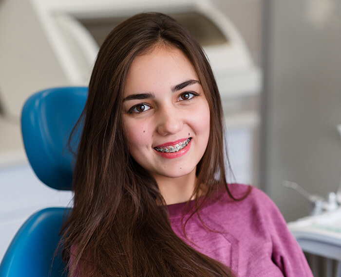 Teen girl with traditional braces smiling