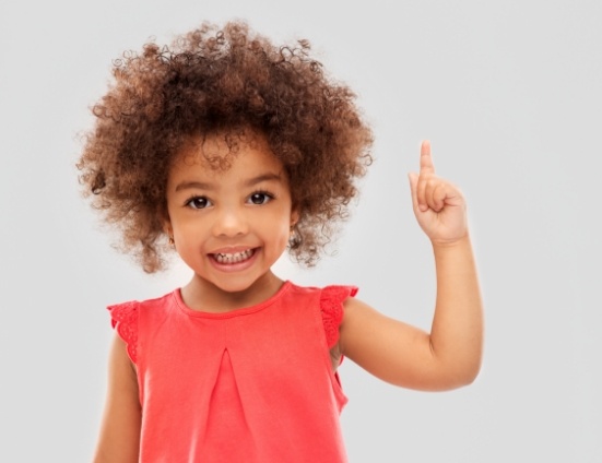 Toddler smiling and pointing their index finger up