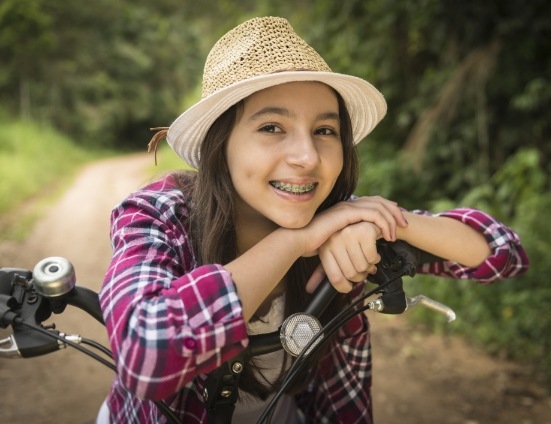 Teenage girl with braces sitting on seat of her bike