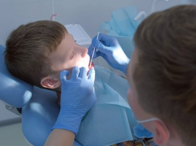 Dentist examining the teeth of a young boy