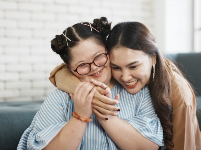 Young woman hugging a smiling girl with special needs