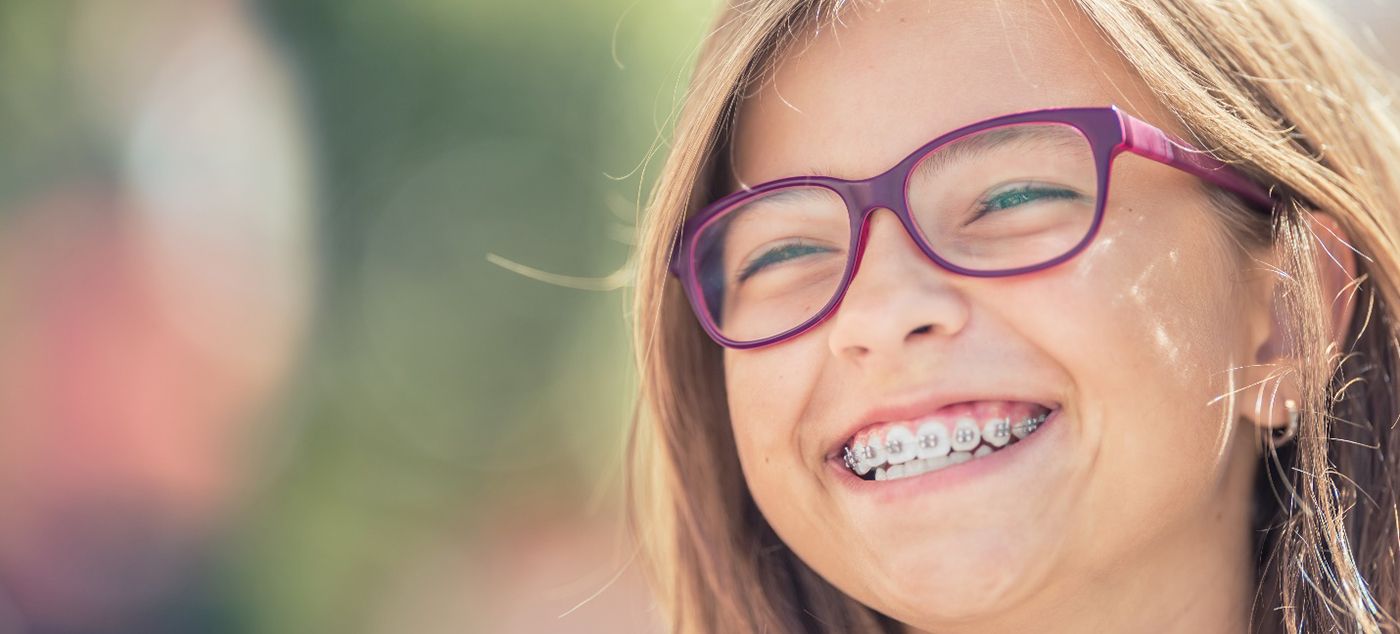 Girl with purple glasses and braces outside smiling