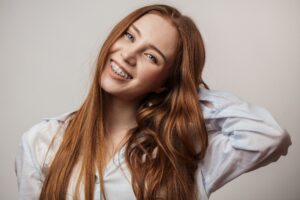 Girl with red hair in pale blue shirt grinning with braces