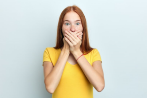 Young woman in yellow T-shirt cupping hands over her mouth